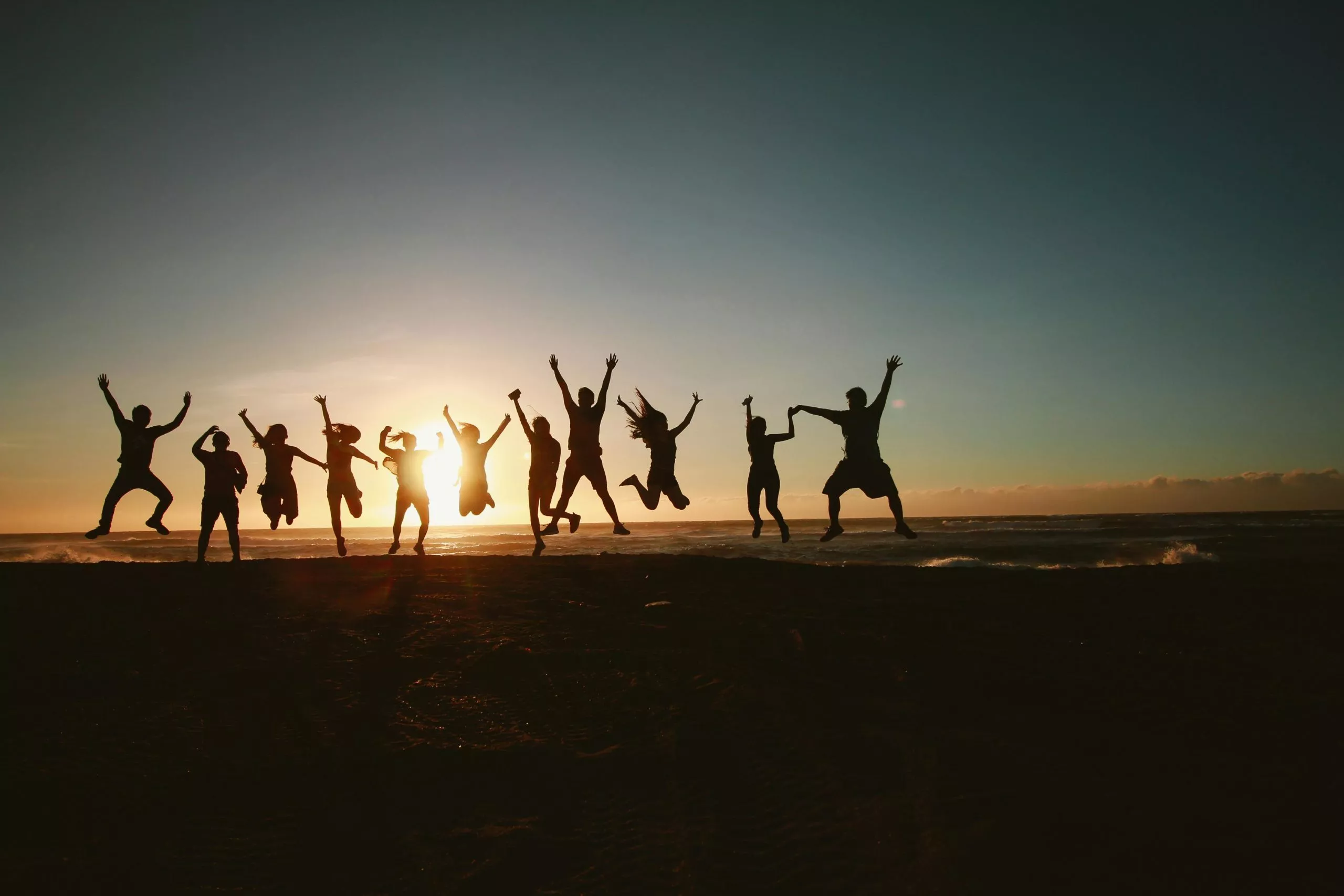 Group of happy people jumping at sunset